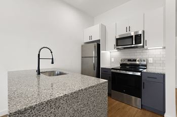 A kitchen with a granite countertop and stainless steel appliances. at Terraces at High Mountain, Huntsville, AL, 35811